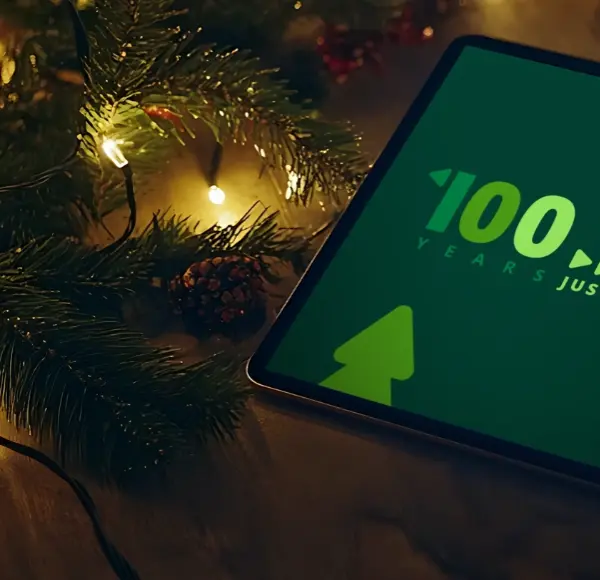 Een tablet met DEKRA 100 jaar op het scherm op de tafel met kerstversiering Een tablet met DEKRA 100 jaar op het scherm op de tafel met kerstversiering