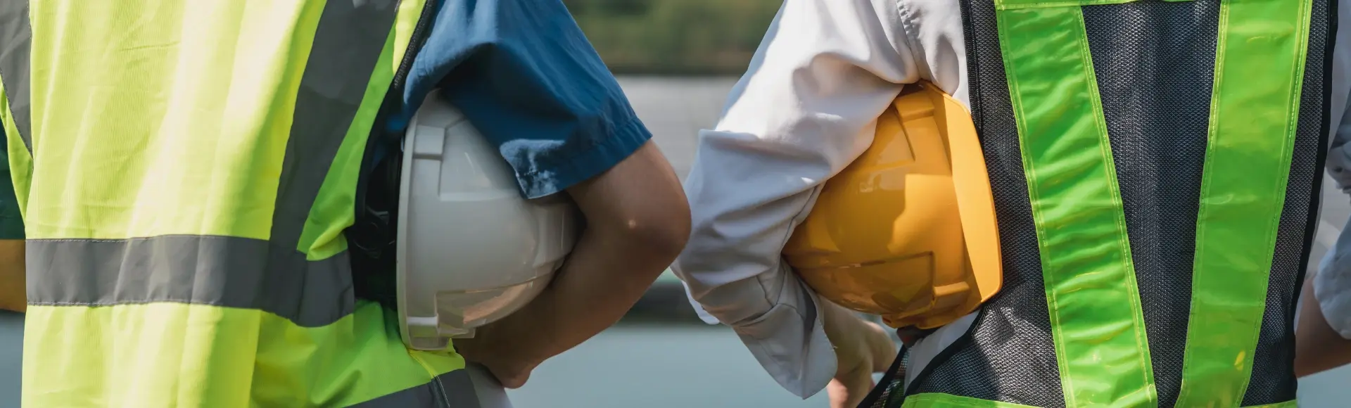 two construction workers side by side with helmet in hand