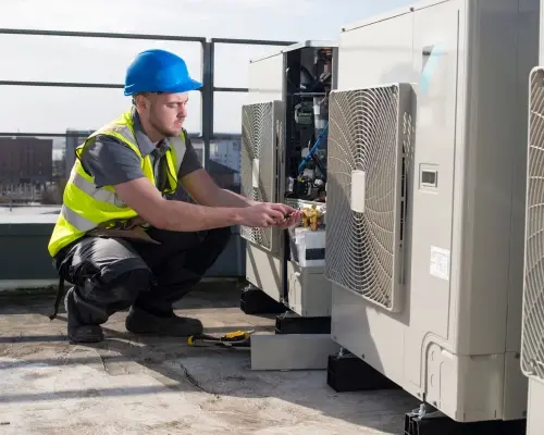 installer works on air conditioning unit on a rooftop