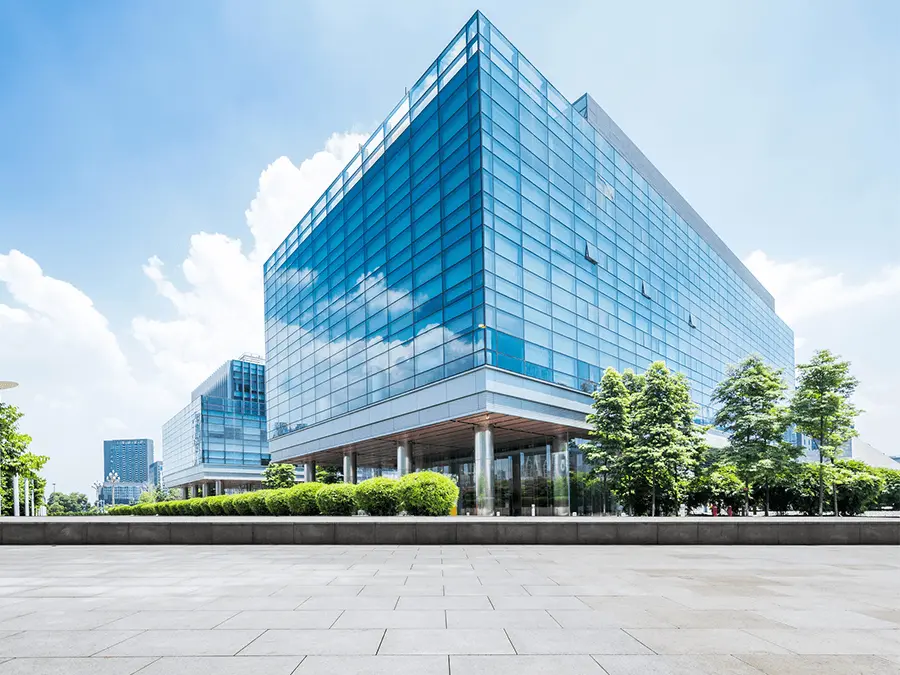 Nowoczesny, przeszklony budynek biurowy otoczony zielenią. Eksploatacja obiektu.