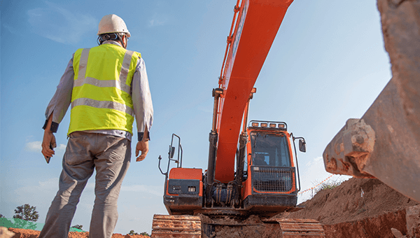 Inżynier na terenie robót ziemnych przy użyciu koparki. Kontrola jakości i nadzór w budownictwie przemysłowym EPC.