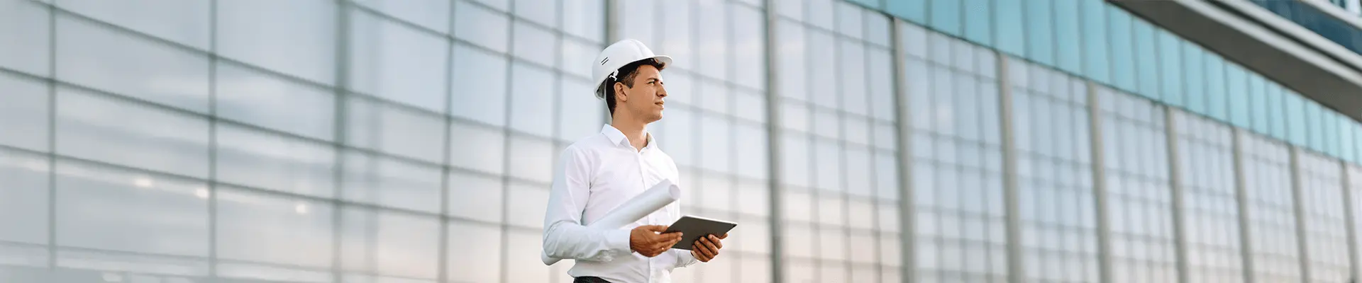 Inżynier z dokumentacją na tle przeszklonego obiektu, kontroluje jakość wykonania robót budowlanych.