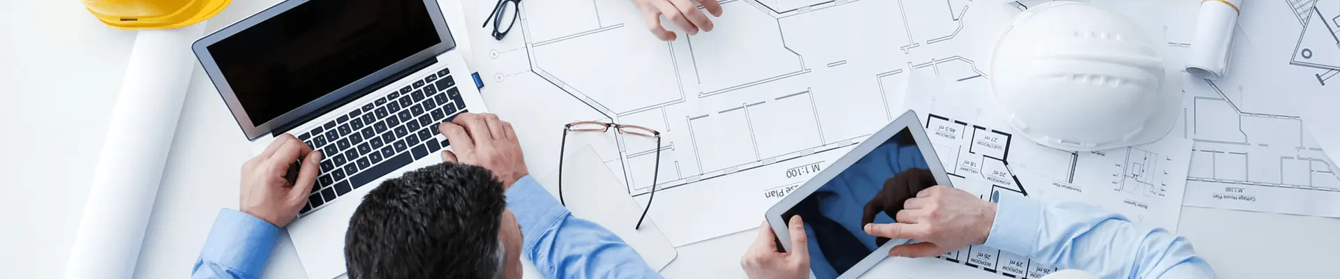 Zespół inżynierów analizujących na stole dokumentację. Koordynacja BHP na placu budowy.