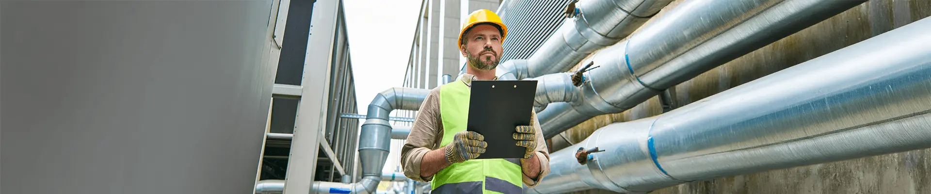 Specjalista w kasku ochronnym i kamizelce odblaskowej dokonujący przeglądu okresowegu budynku.