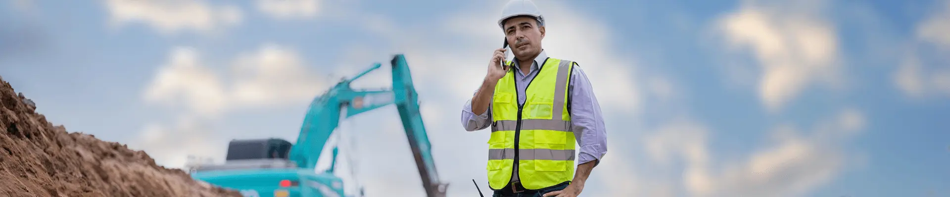 Inżynier na placu budowy z maszynami i dźwigiem w tle. Realizacja inwestycji budowlanej.