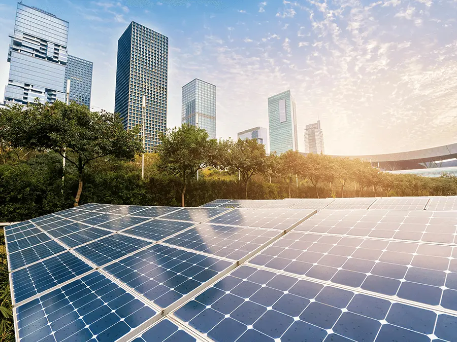 Panele solarne na tle nowoczesnych wieżowców. Transformacja energetyczna budownictwa. 