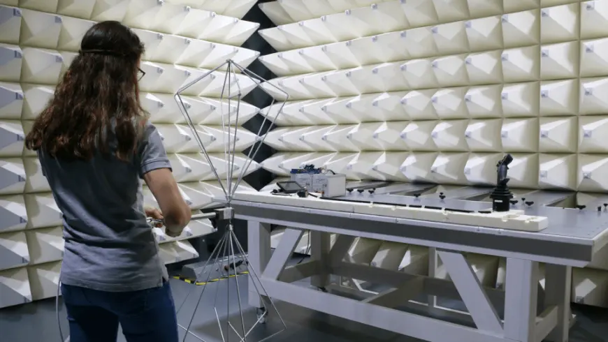 Woman conducting EMC measurements in an anechoic test chamber with wave-absorbing panels