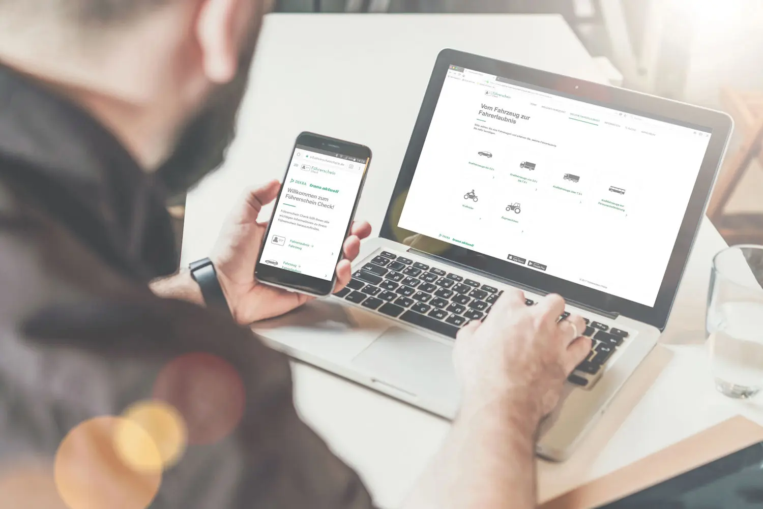 Nutzer sitzt mit Smartphone in der Hand vor Laptop
