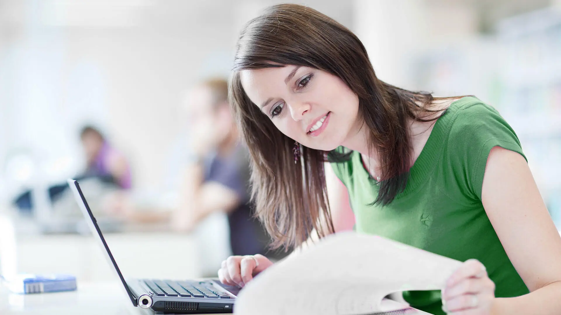 Lady reading a report in front of a laptop