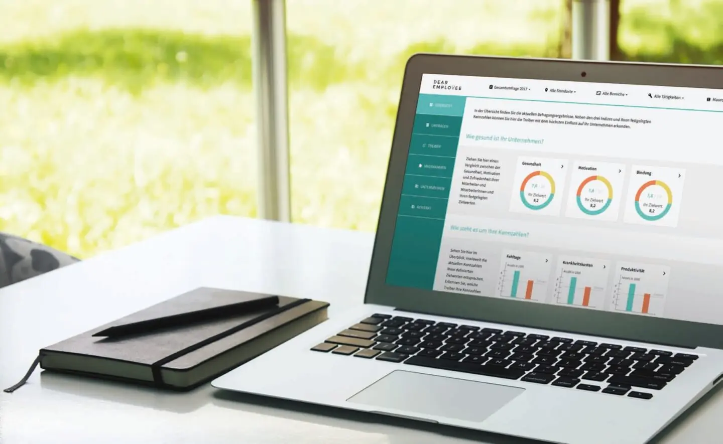 Laptop und Notizbuch auf Tisch vor Fenster