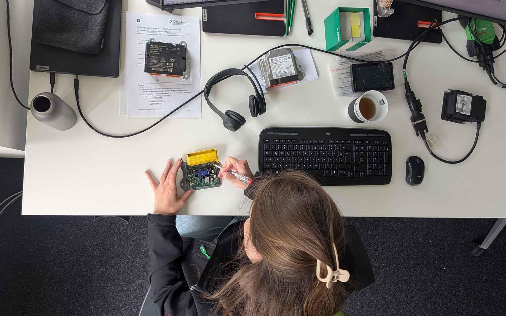 A DEKRA expert evaluates a removed airbag control unit at her workstation.