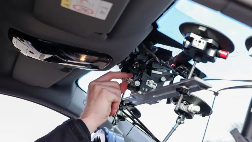  A DEKRA employee’s hand adjusts a mount installed on the inside of the windscreen in a test vehicle, allowing the ADAS camera to be finely repositioned for test runs.