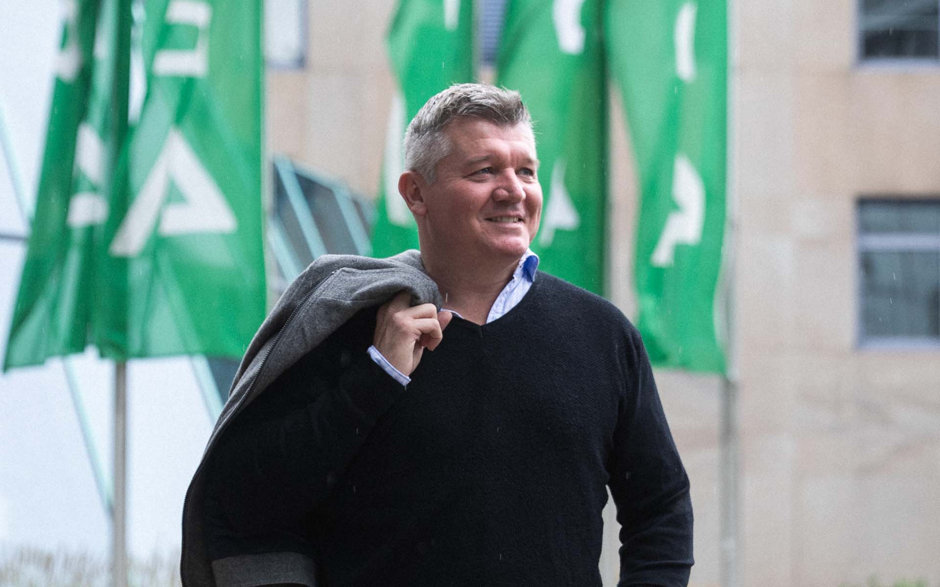 DEKRA cybersecurity expert Graham Stanforth in front of a building with flags.