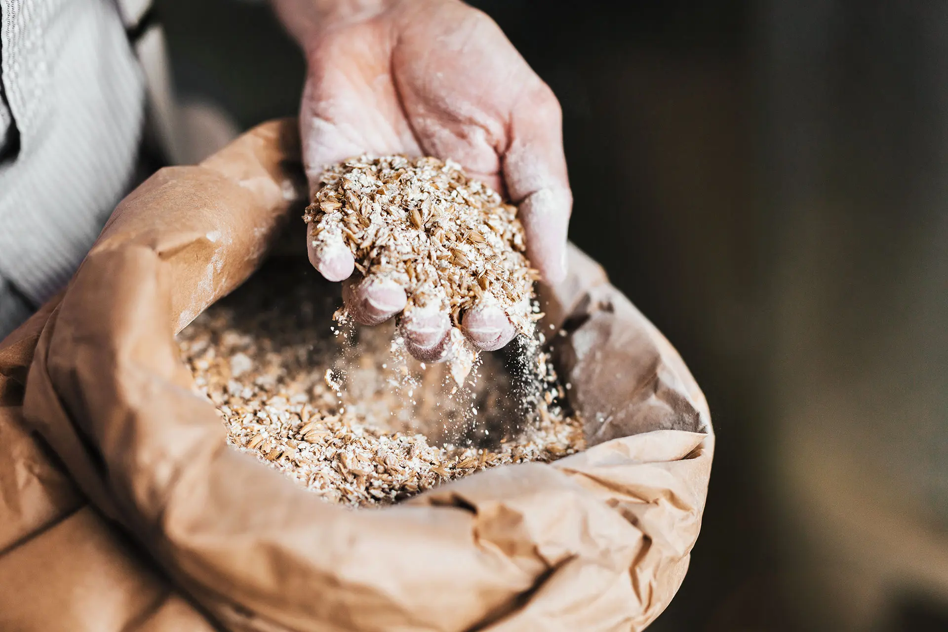 Hand greift in einen Sack mit Getreide