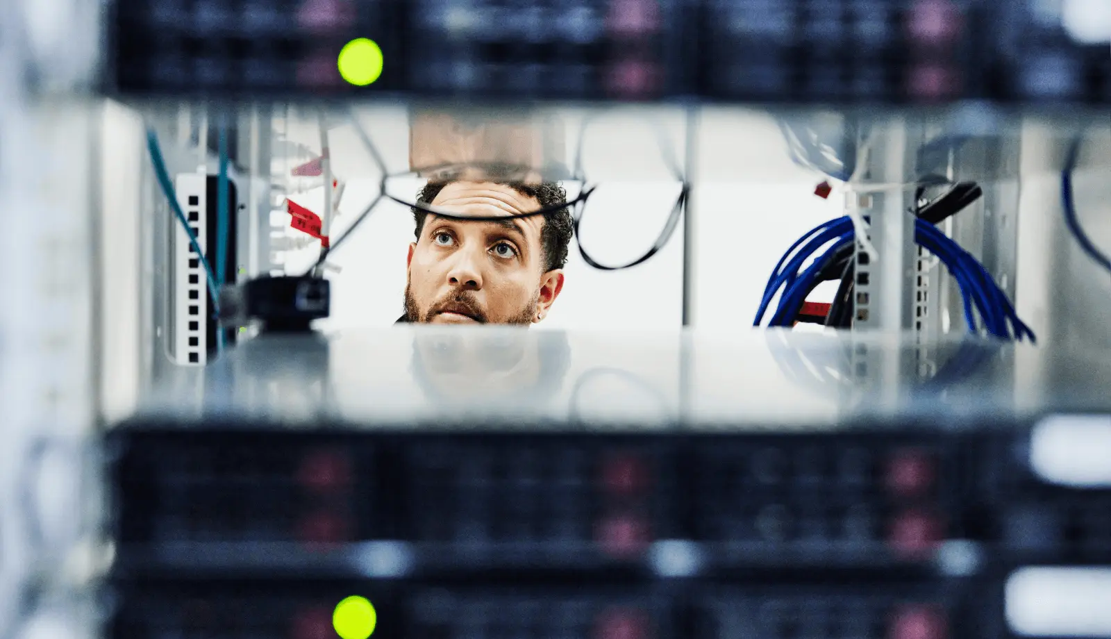 A shot of a male IT professional working in a data center between server racks.