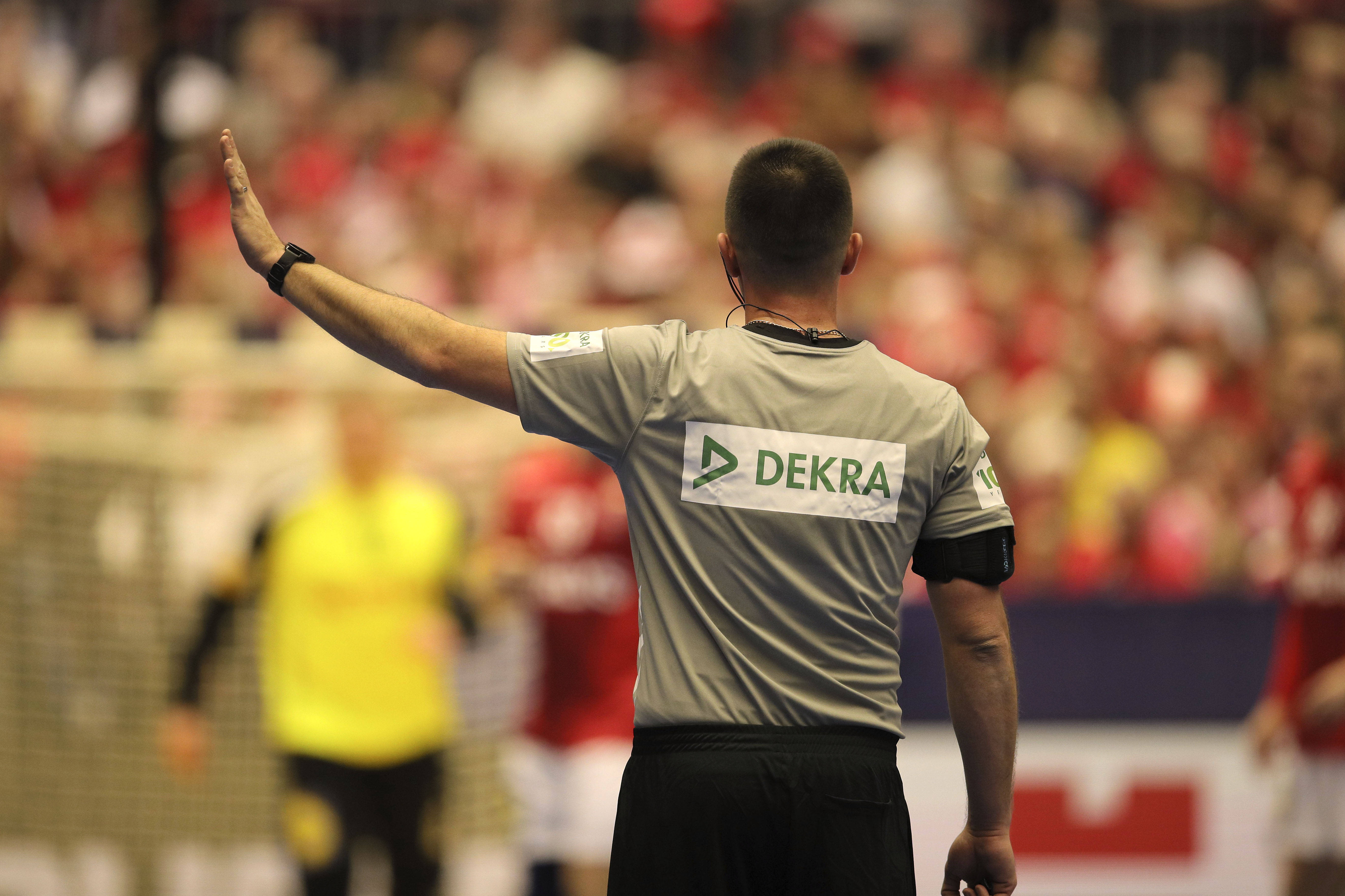 A male referee wearing a jersey with the DEKRA logo on it