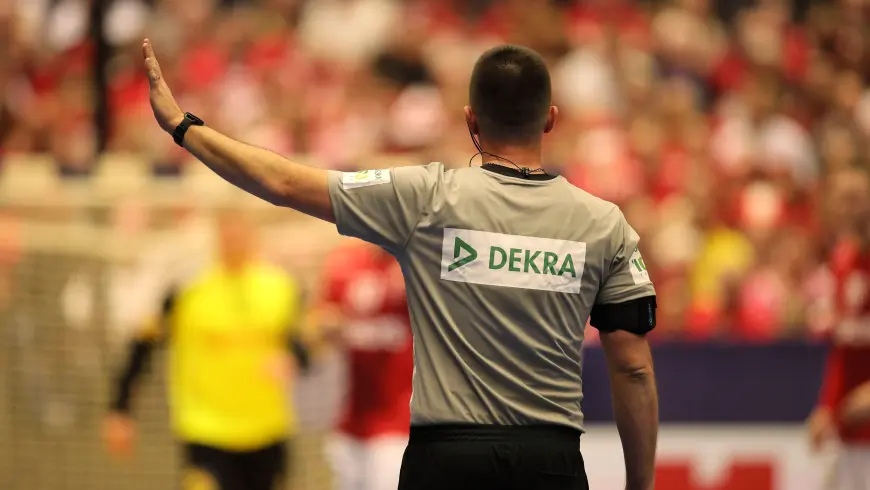 A male referee wearing a jersey with the DEKRA logo on it