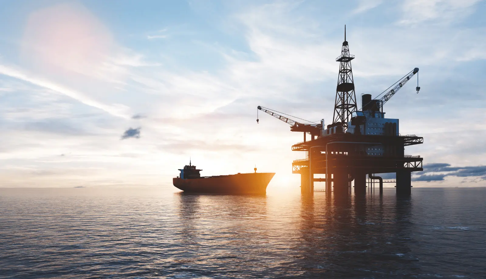 An oil platform and a ship on the ocean with a sunset in the background.