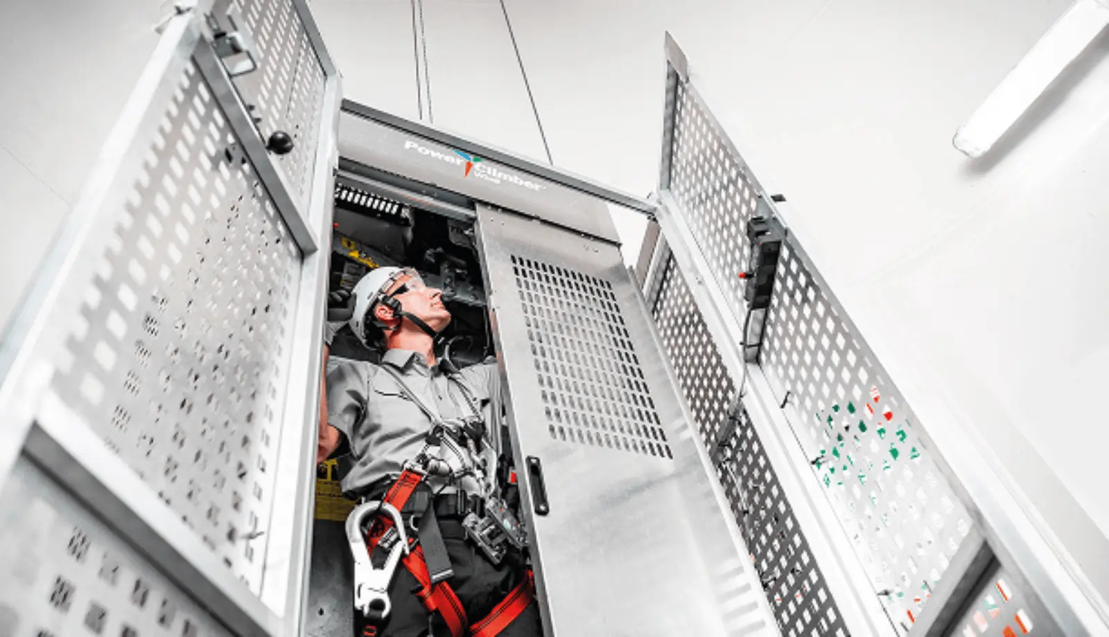 A technician in a service lift in a wind turbine, wearing a full set of personal fall protection equipment (PFPE) to work safely at height.