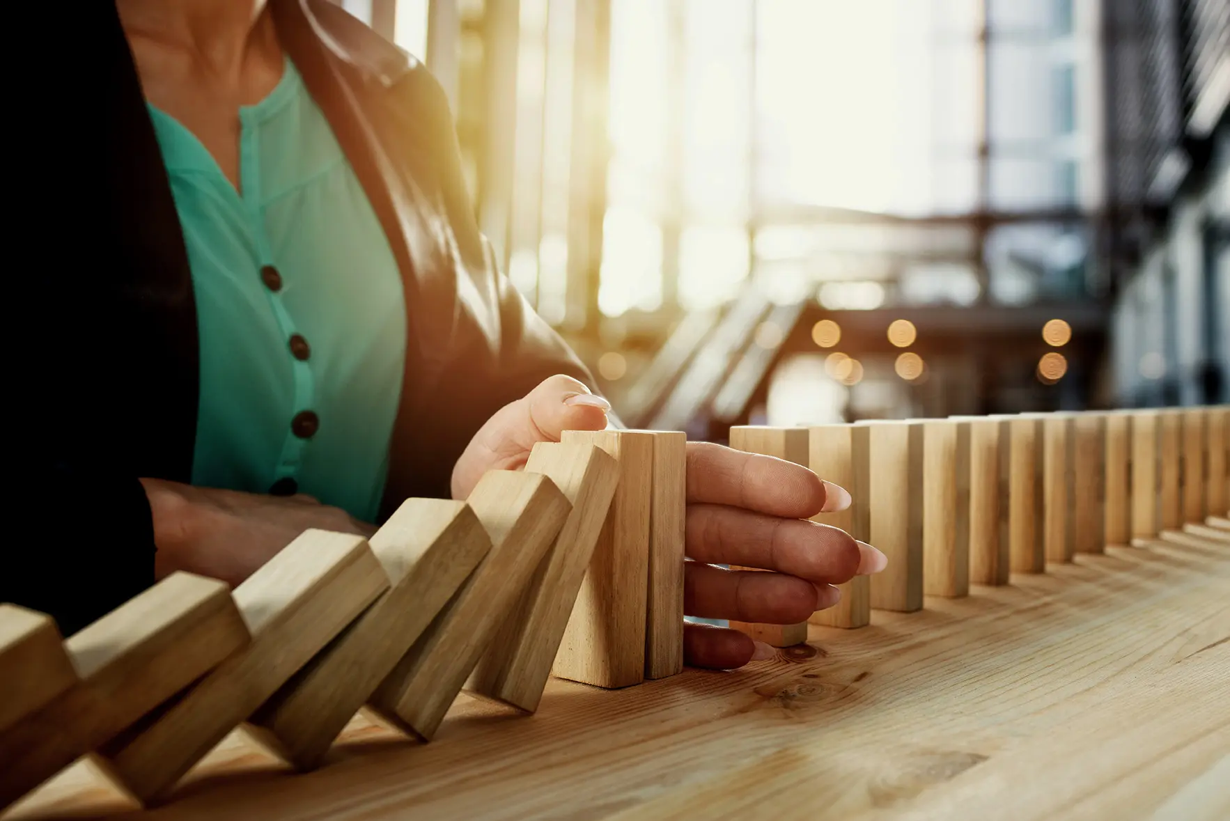 A hand stops the fall of dominos