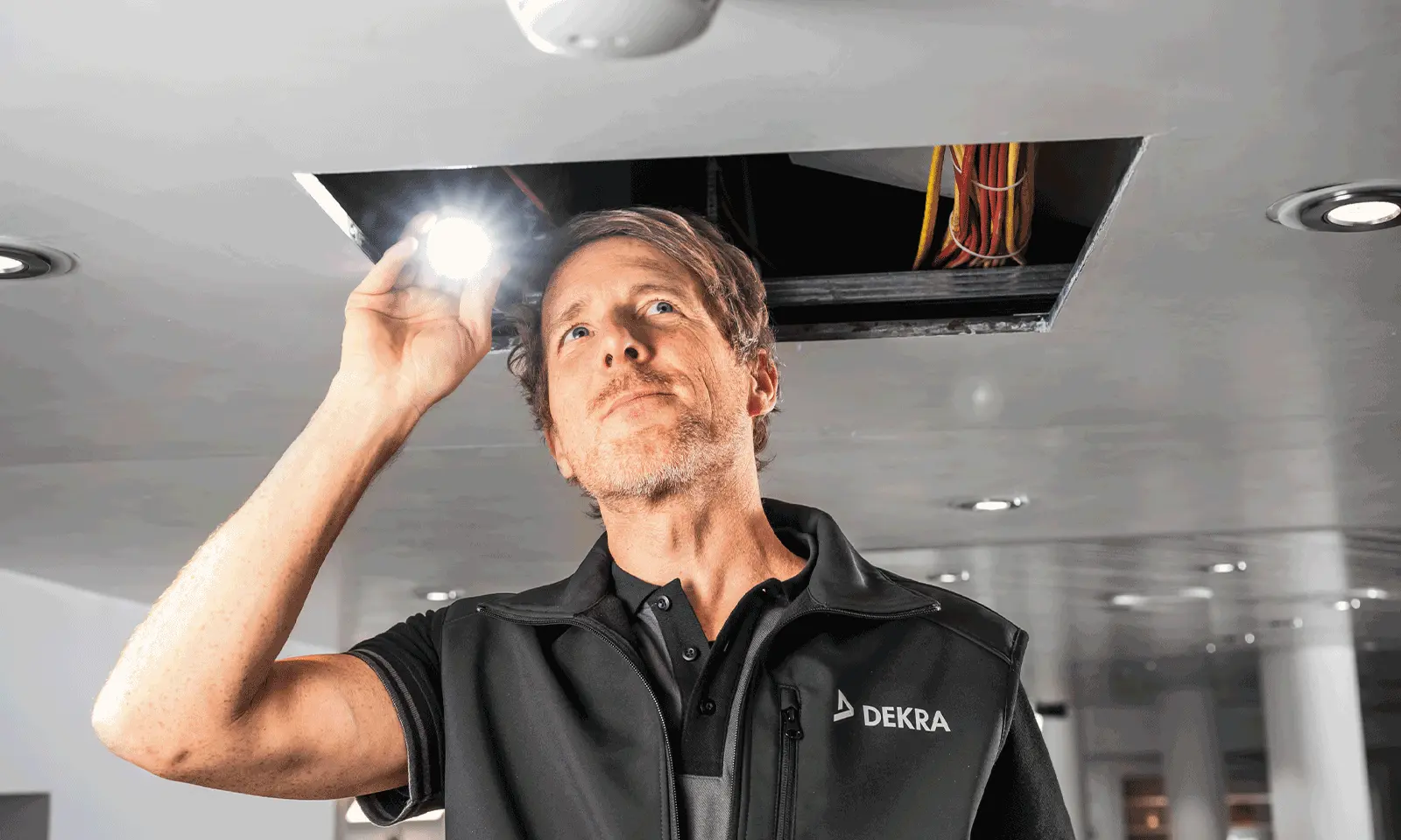 DEKRA expert testing fire detection system in a commercial space for functionality and compliance.