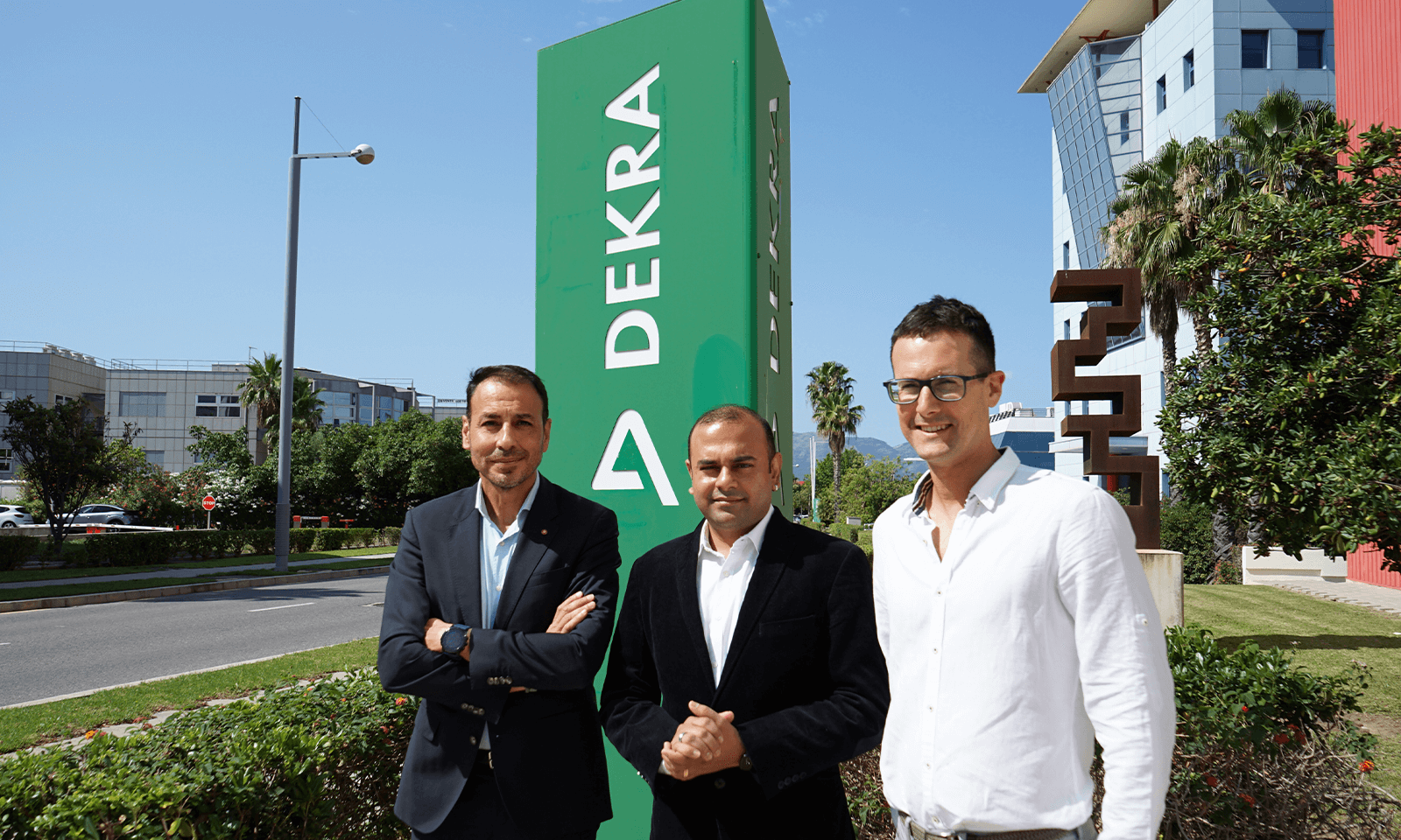 Men standing in front of DEKRA sign