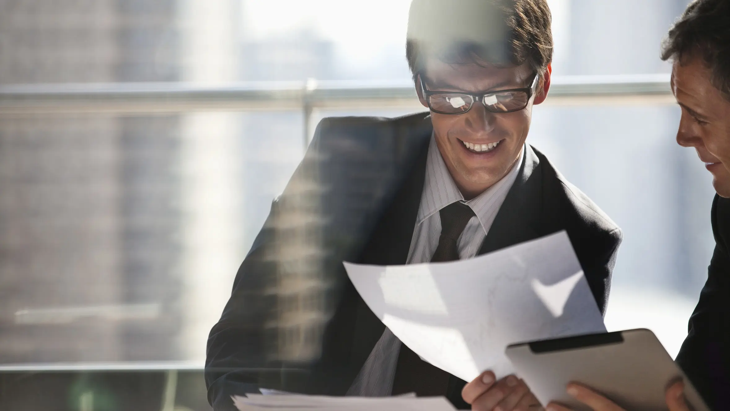 Glimlachende man met bril bekijkt opgehouden pagina's papier