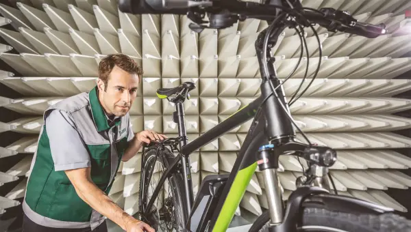 DEKRA Sachverständiger hält ein E-Bike auf dem Prüfstand DEKRA Sachverständiger hält ein E-Bike auf dem Prüfstand