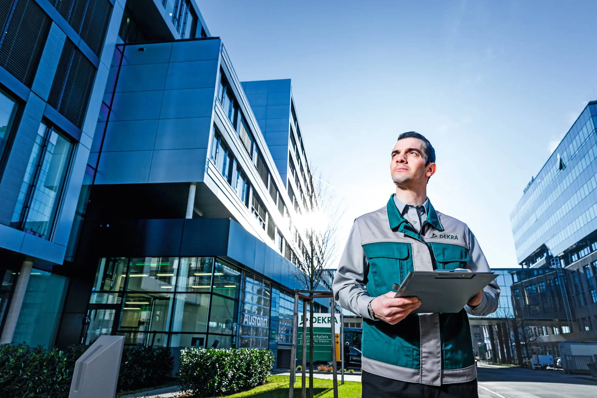Unternehmer blickt mit Tablet in der Hand auf Geschäftsgebäude