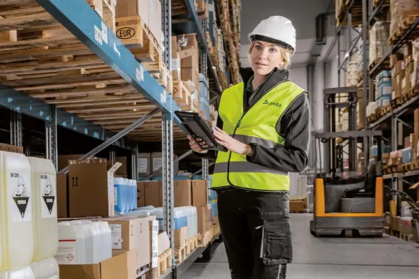 Frau mit Arbeitskleidung in einer Industriehalle Frau mit Arbeitskleidung in einer Industriehalle