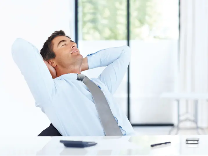 Mitarbeiter streckt am Arbeitsplatz den Rücken