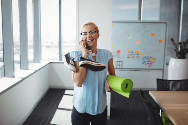 Frau am telefonieren mit einer Sportmatte in der Hand