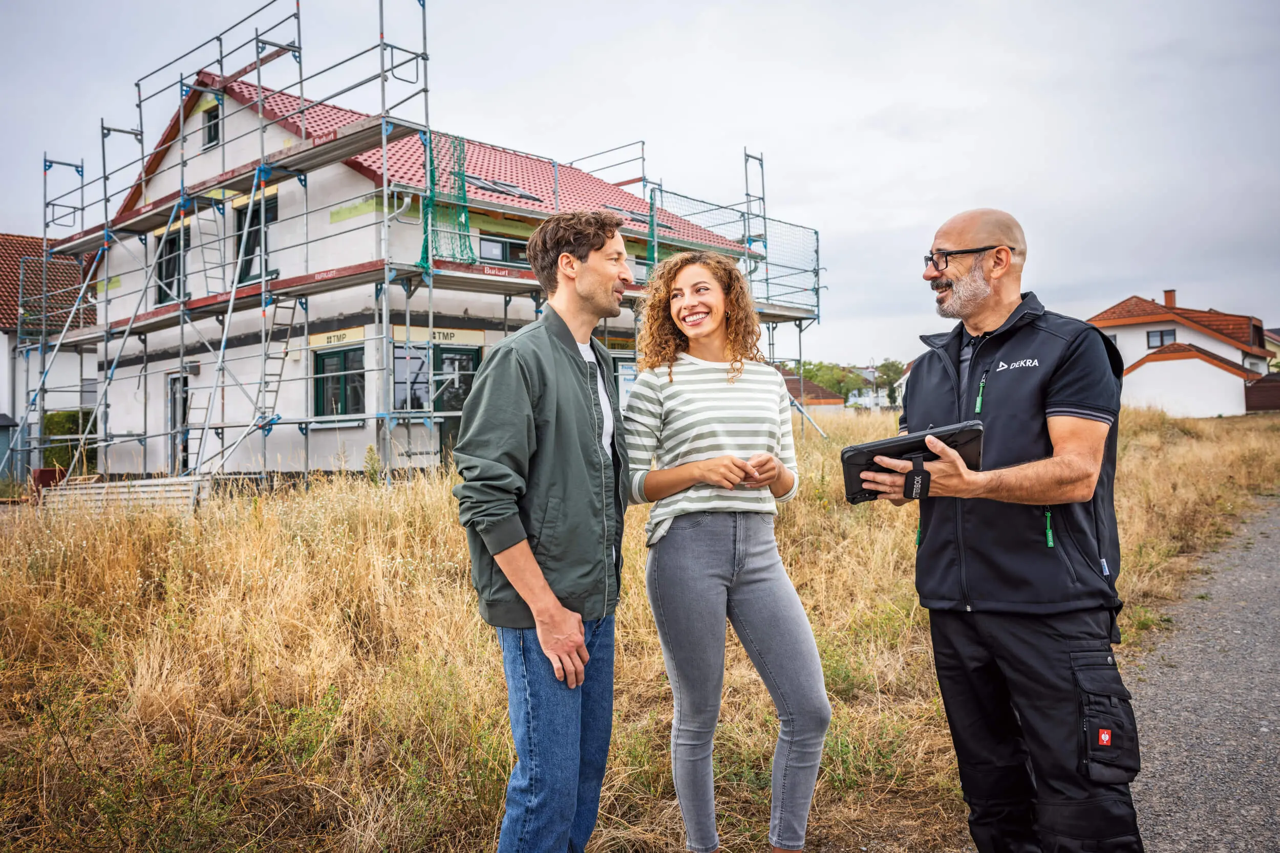 DEKRA Immobilienprüfer steht mit Kunden vor Haus