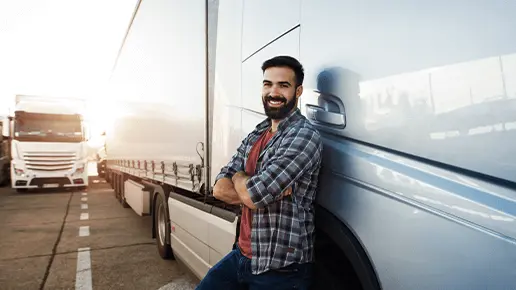Lkw-Fahrer lehnt sich zufrieden an Lkw auf Parkplatz 