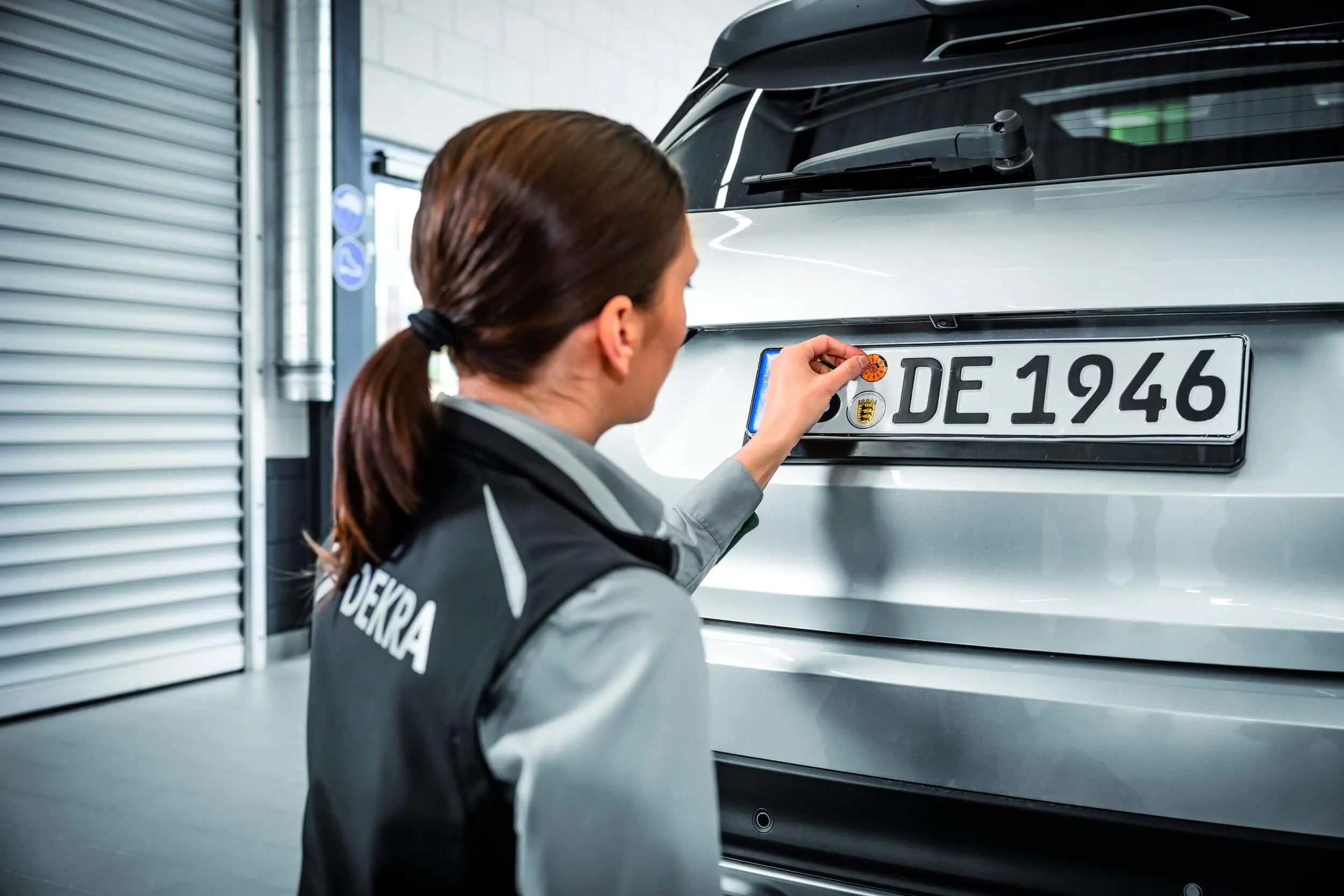 DEKRA Experte klebt HU-Plakette auf Nummernschild