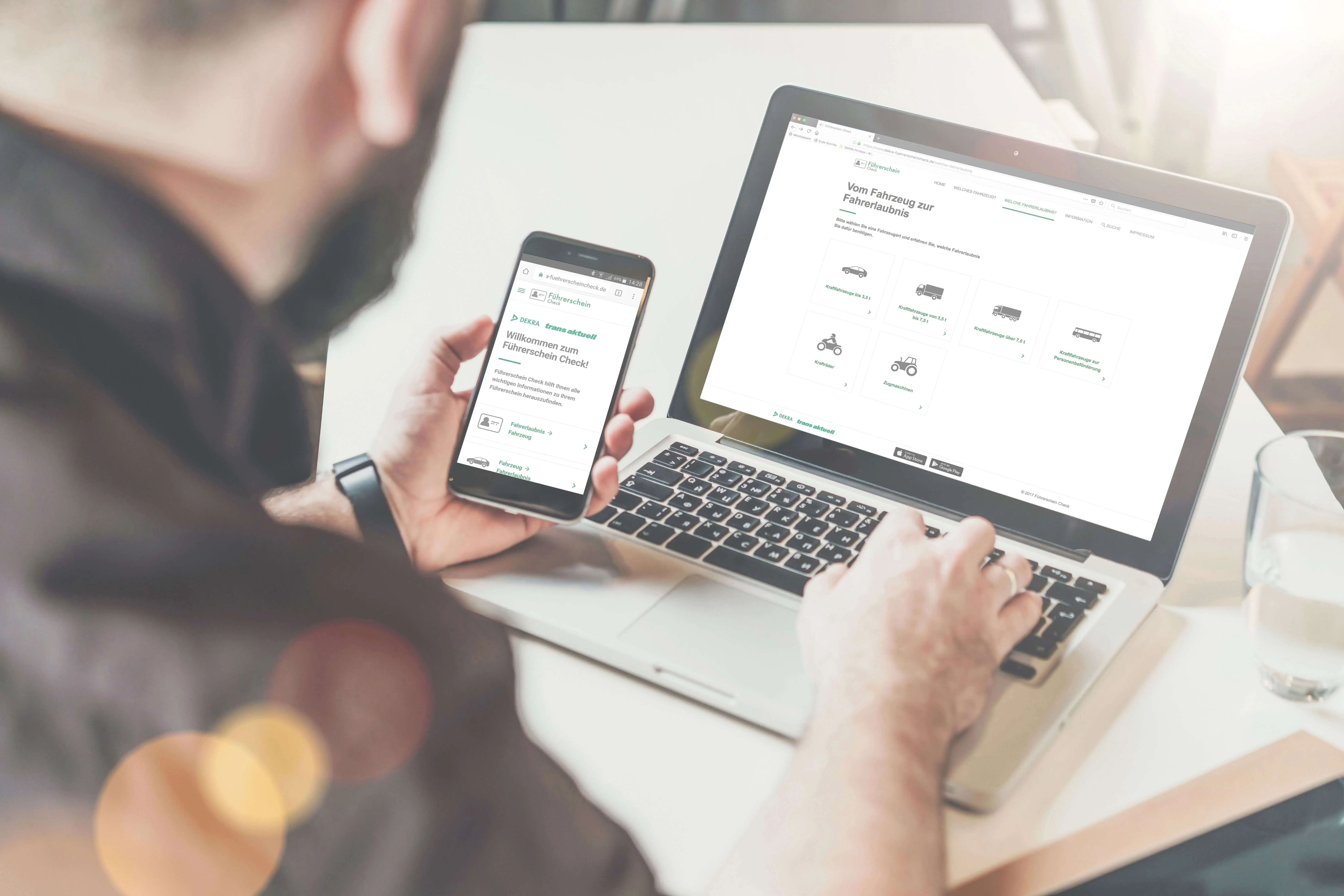 Nutzer sitzt mit Smartphone in der Hand vor Laptop