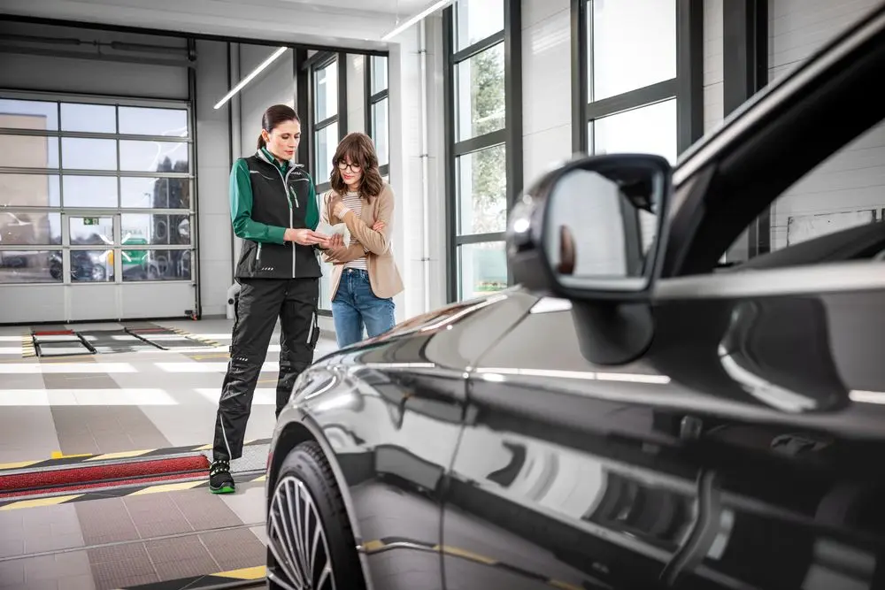 DEKRA Experte mit Geschäftsmann an geöffneter Fahrertür eines PKW