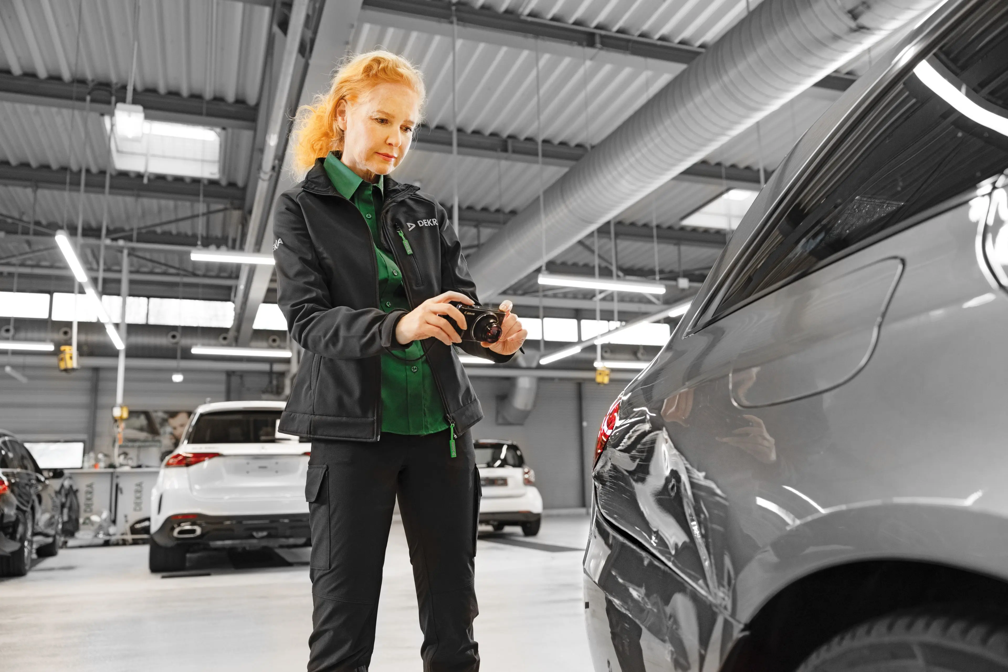 DEKRA Experte hält Messgerät an Fahrzeug DEKRA Experte hält Messgerät an Fahrzeug