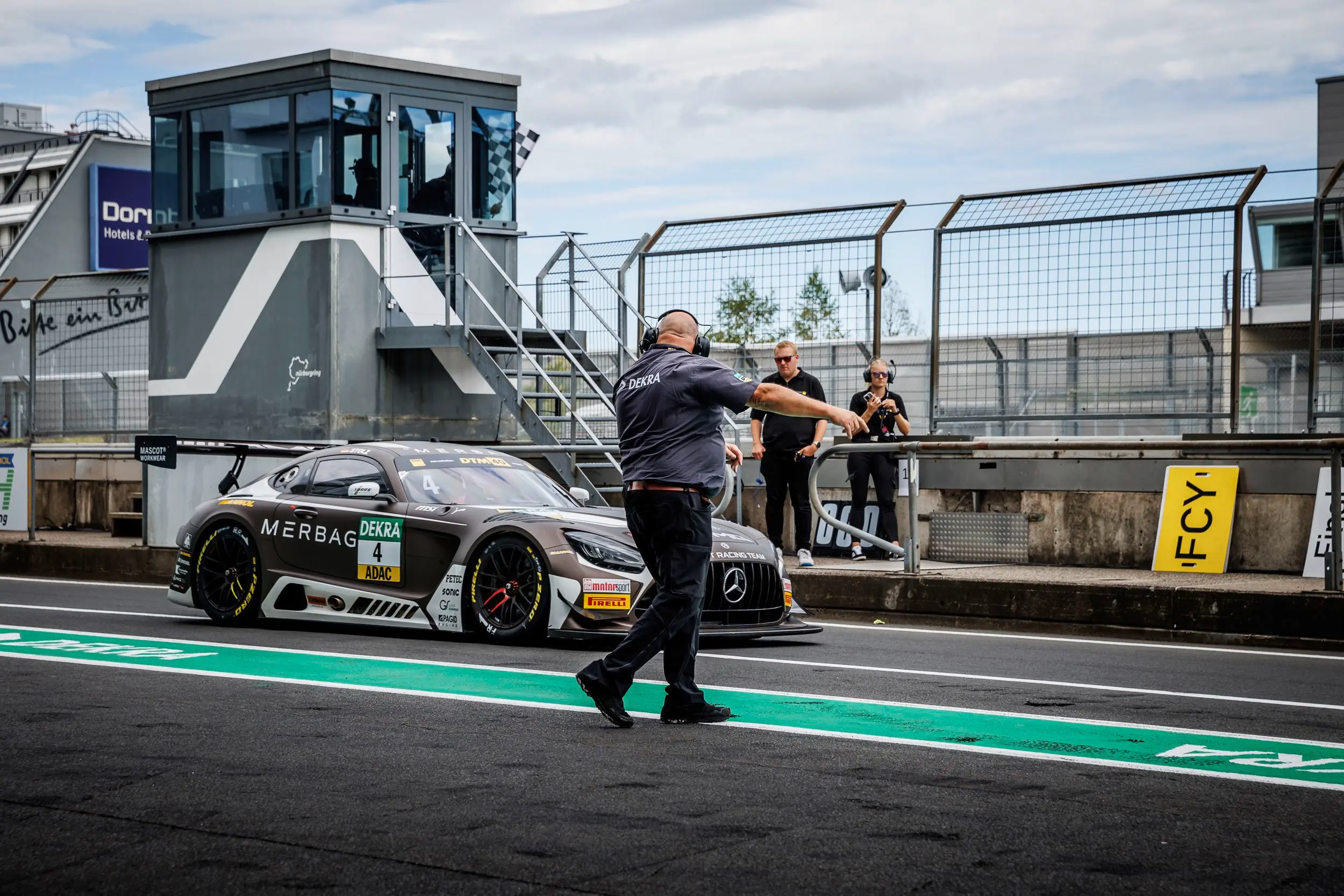 Technischer Kommissar mit gelber Flagge weist DTM-Rennwagen ein Technischer Kommissar mit gelber Flagge weist DTM-Rennwagen ein