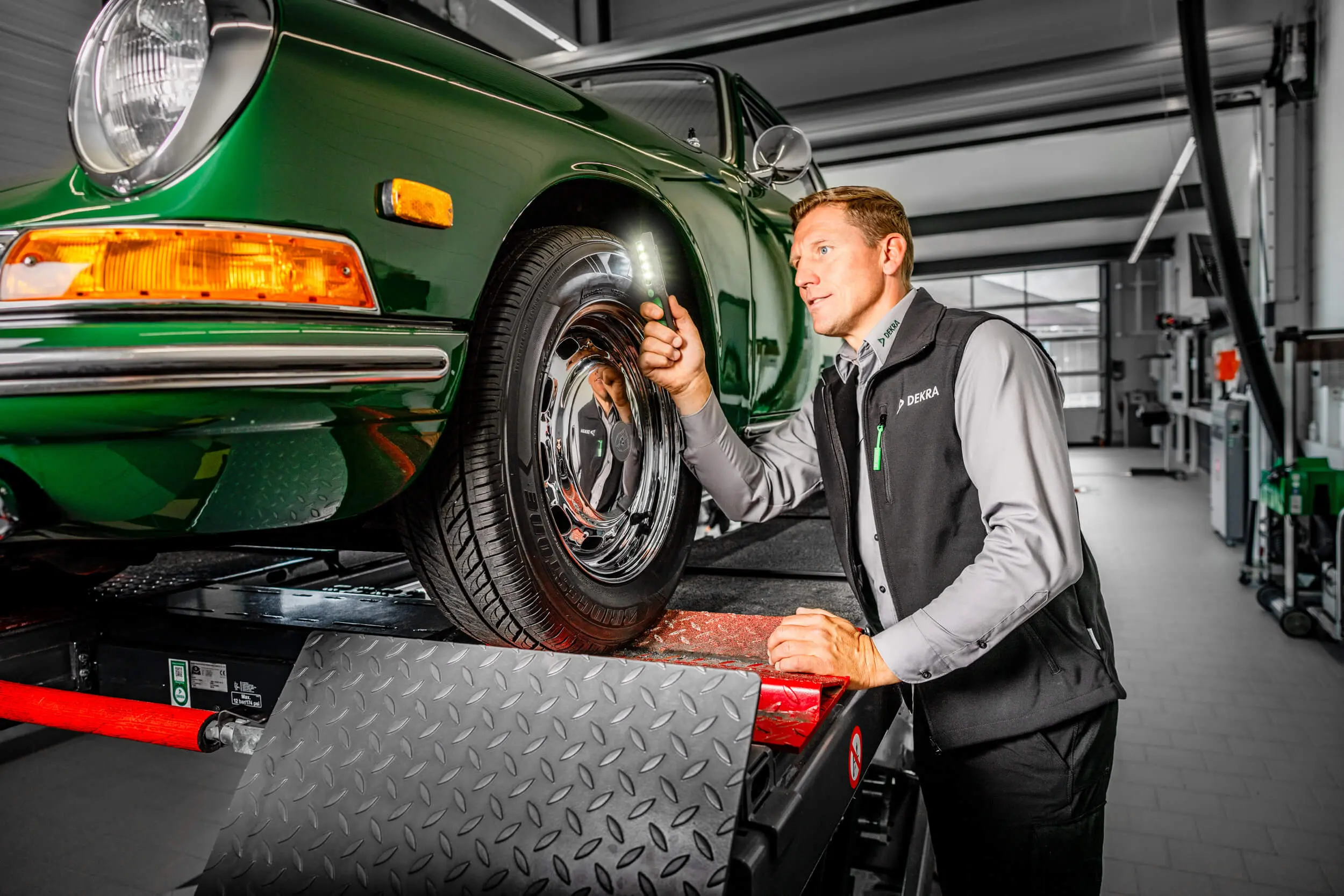 DEKRA Fahrzeugbewerter prüft die Reifen eines Oldtimers auf einer Hebebühne