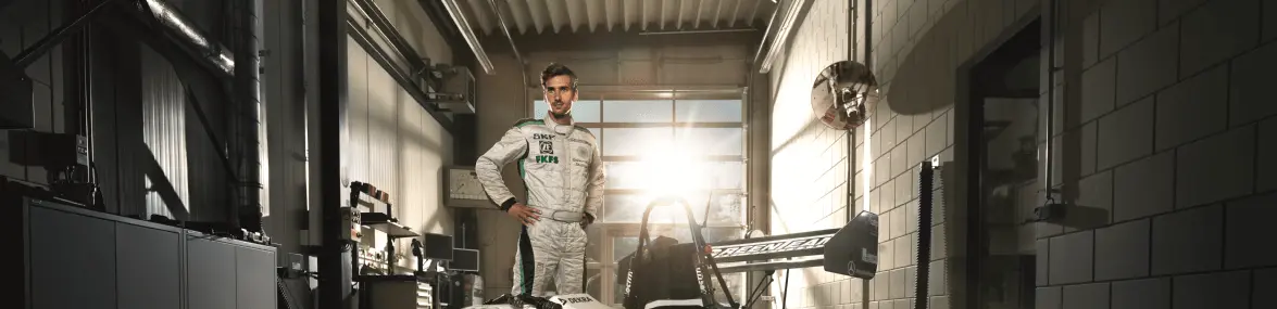 Formula-Student-Fahrer in Rennanzug vor Rennwagen