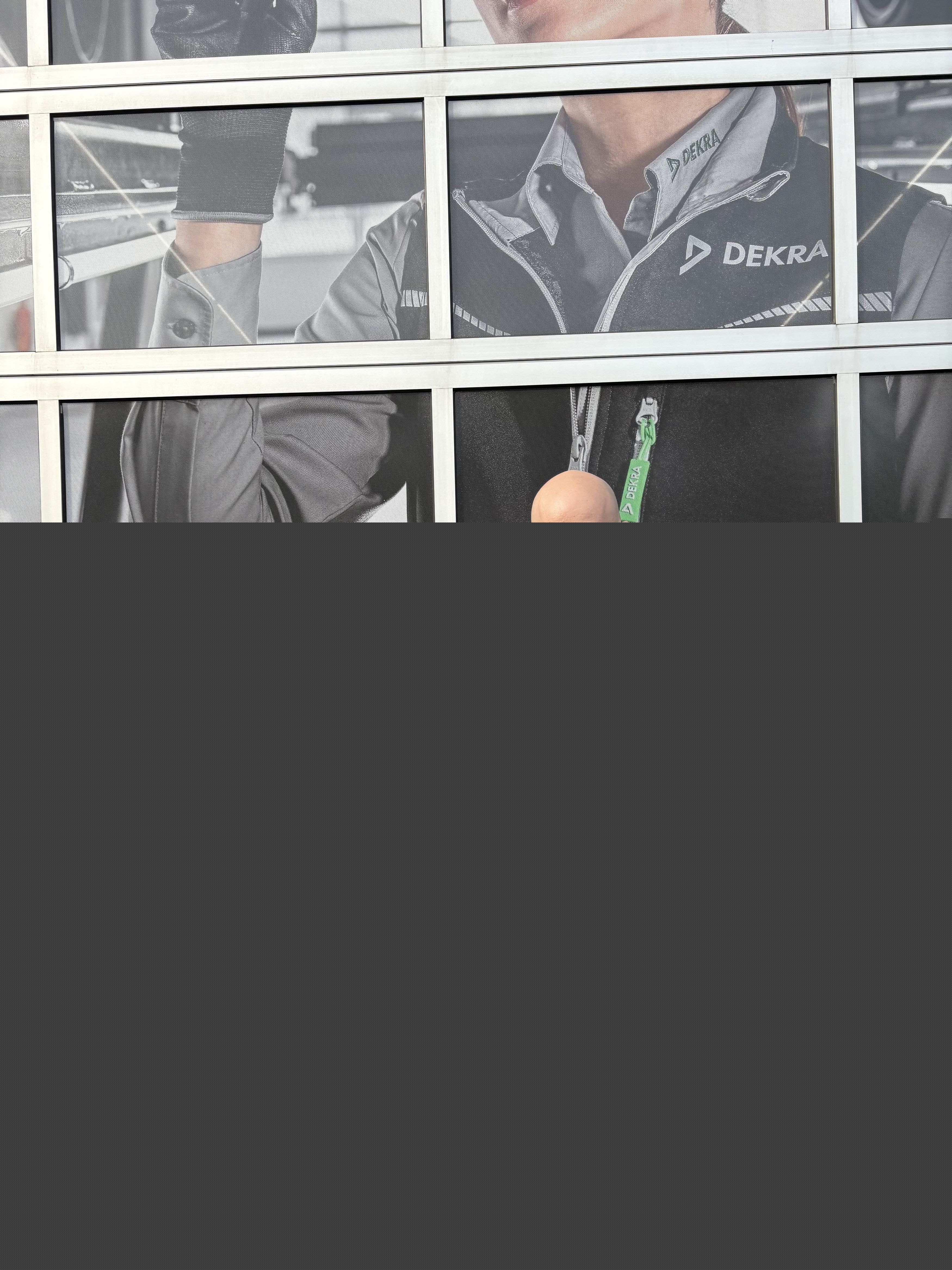 Girolamo & Florian in Arbeitskleidung vor dem Tor einer DEKRA Prüfhalle