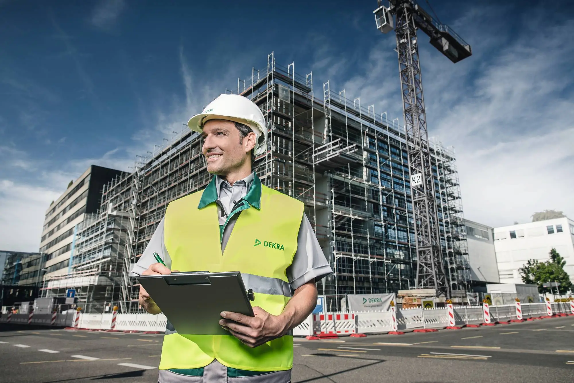 DEKRA Bausachverständiger mit Klemmbrett steht vor Rohbau