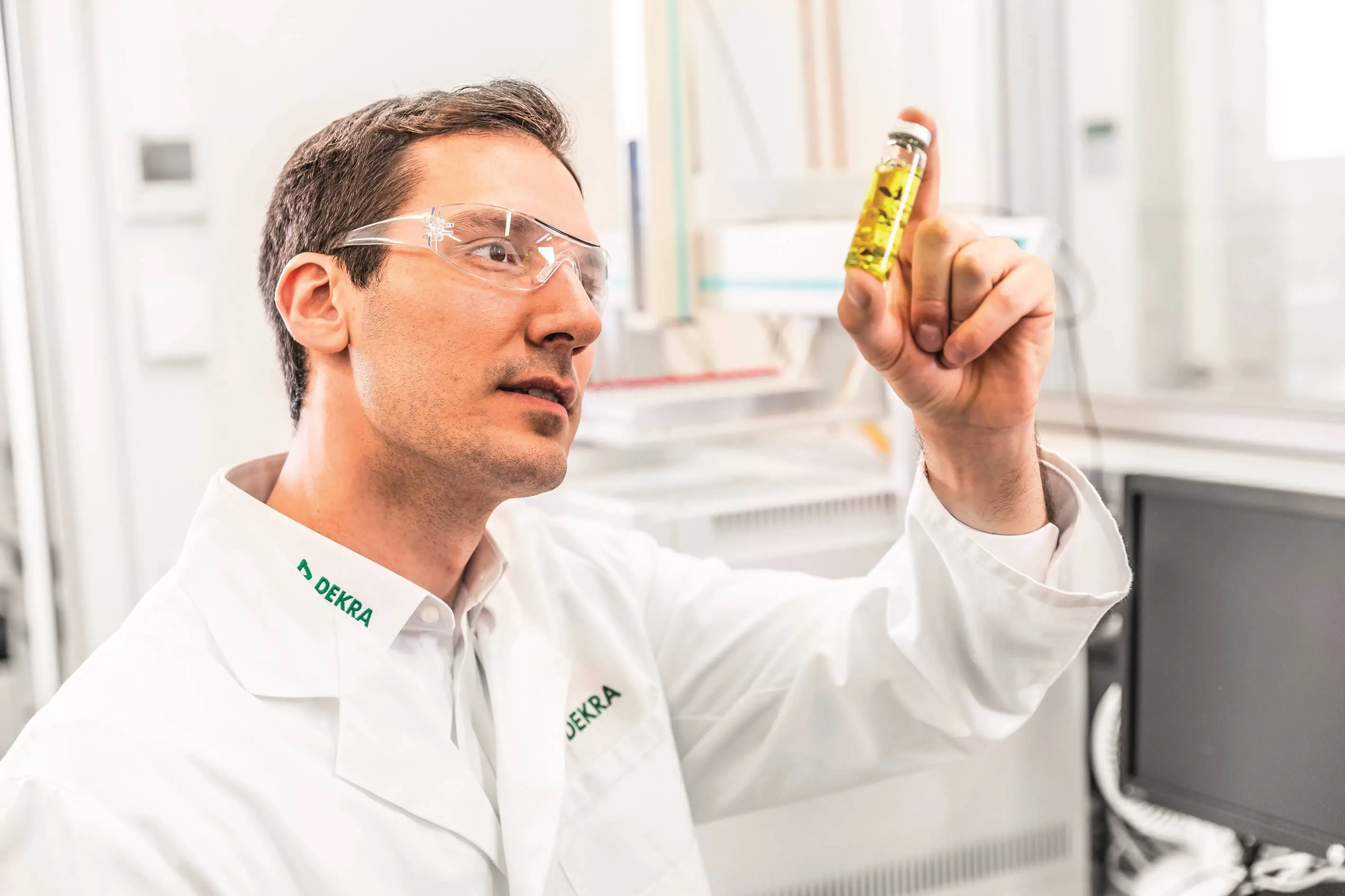 Labormitarbeiter schaut auf Probenglas