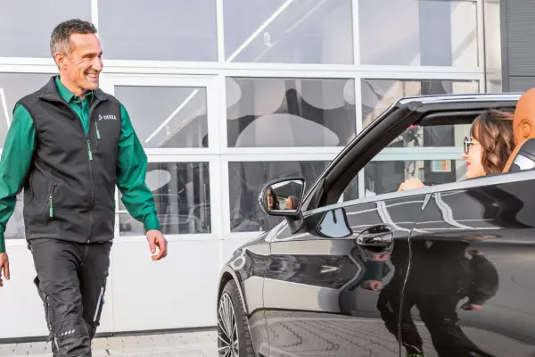 DEKRA Experte steht neben Cabrio mit Frau am Steuer