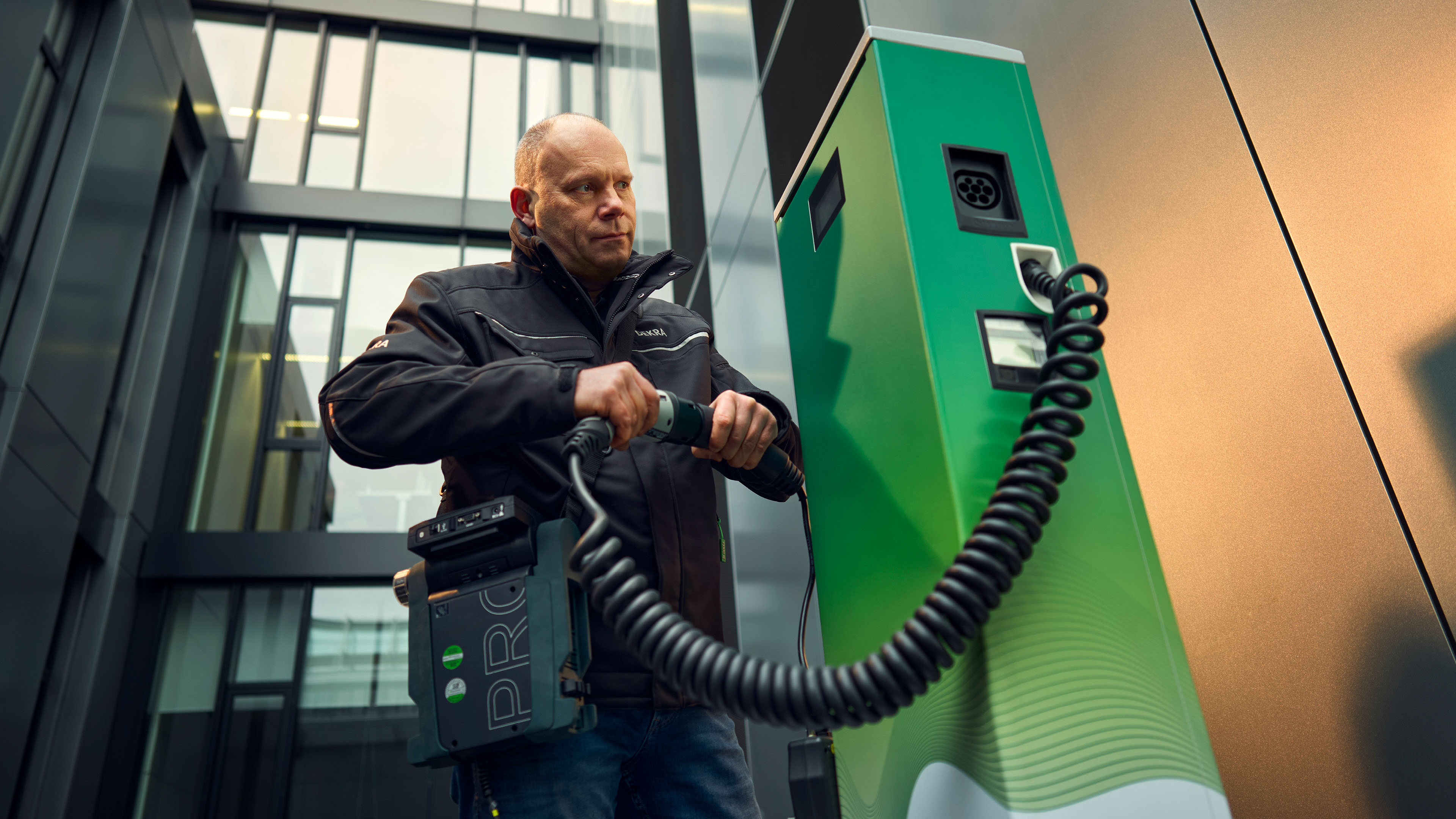 Michael Ringleb, Produktbetreuer für Elektromobilität bei DEKRA, in Arbeitskleidung bei der Prüfung einer E-Ladesäule