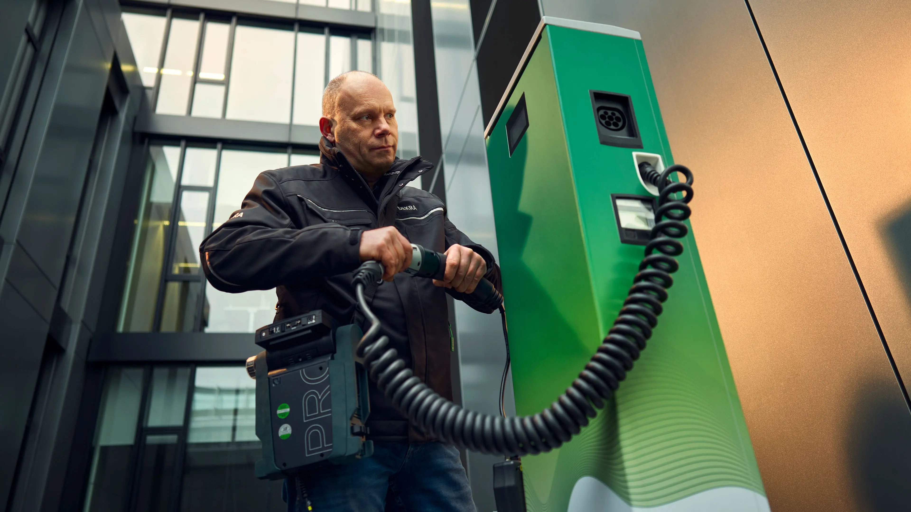 Michael Ringleb, Produktbetreuer für Elektromobilität bei DEKRA, in Arbeitskleidung bei der Prüfung einer E-Ladesäule