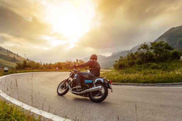 Motorrad in einer Kurve Richtung Sonnenuntergang