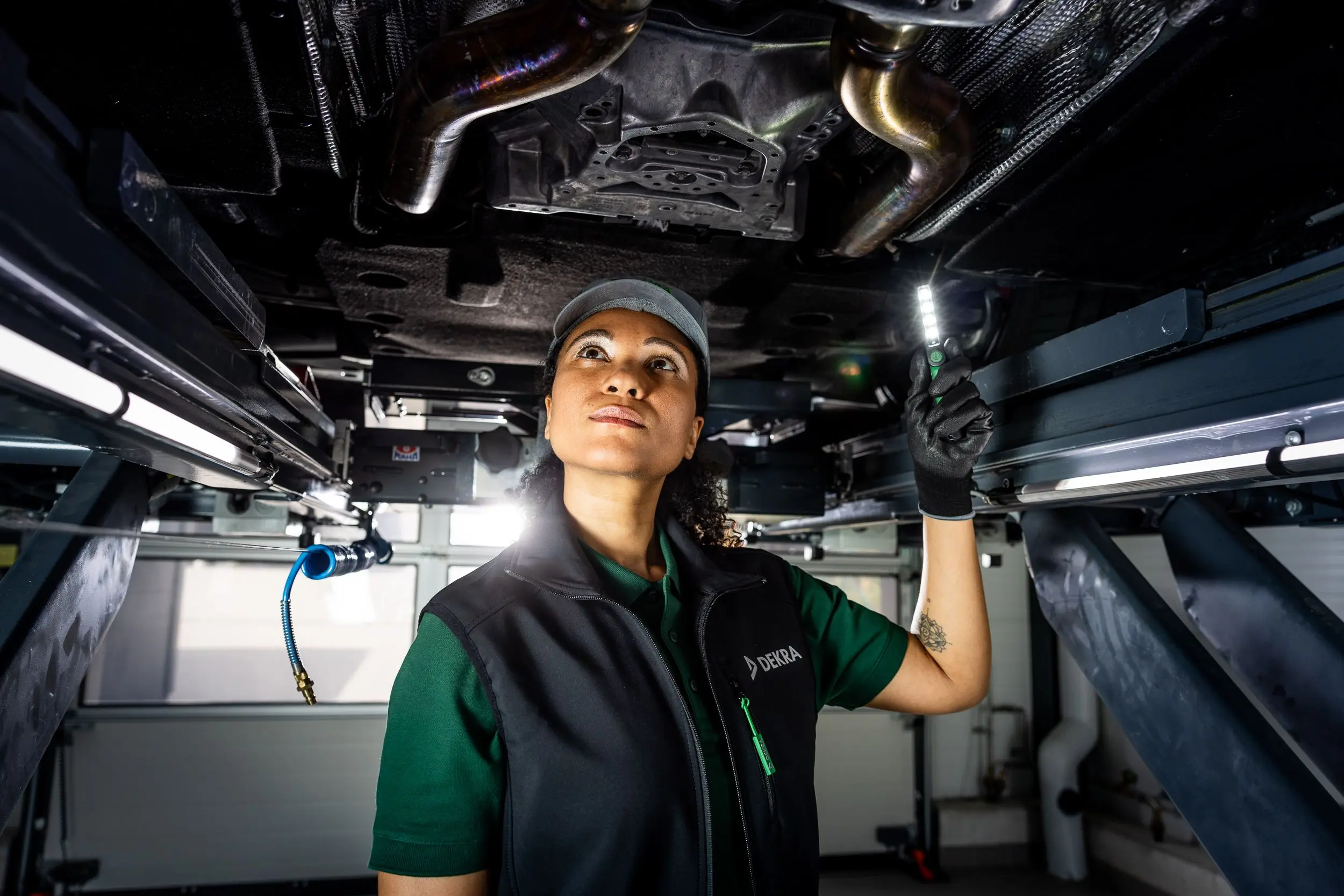 DEKRA Sachverständige unter einem Auto auf einer Hebebühne