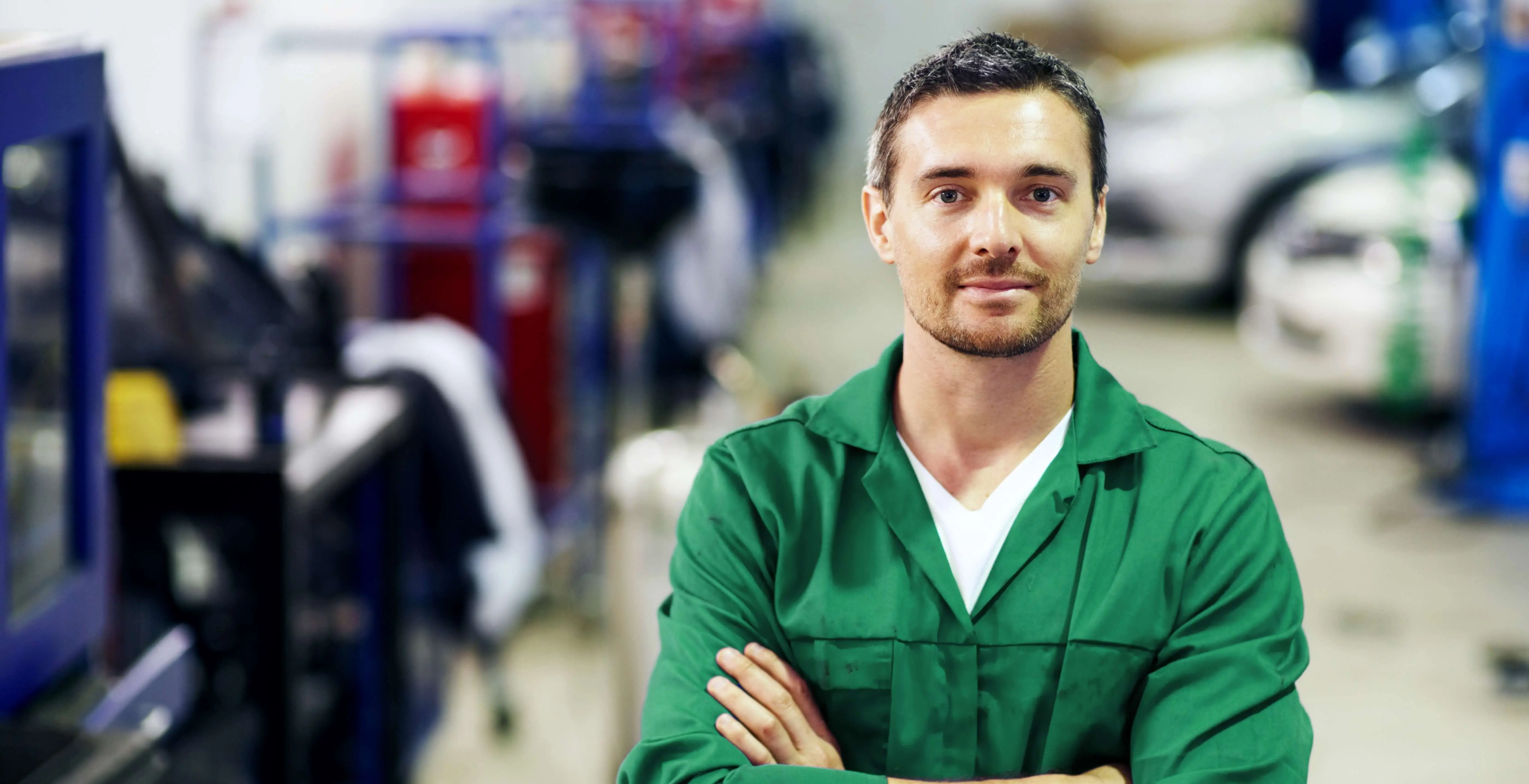 Angestellter mit einer Mechanikerwerkstatt im Hintergrund Angestellter mit einer Mechanikerwerkstatt im Hintergrund